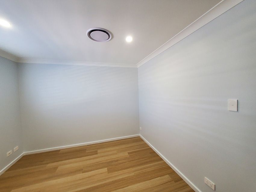 An Empty Room with White Walls and Wooden Floors — JWP Painting & Property Services in Ettalong Beach, NSW
