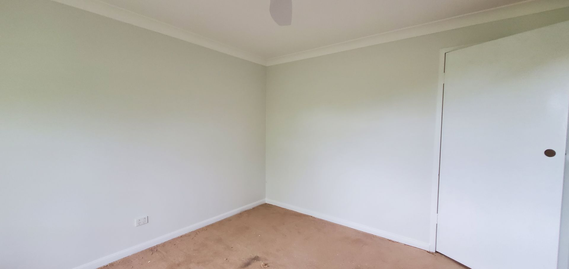 An Empty Room With a Ceiling Fan and a Door — JWP Painting & Property Services in Ettalong Beach, NSW
