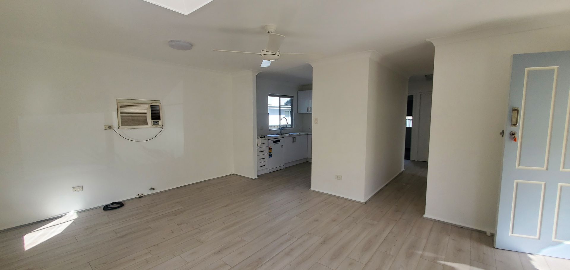 An Empty Living Room With a Ceiling Fan and a Blue Door — JWP Painting & Property Services in Ettalong Beach, NSW