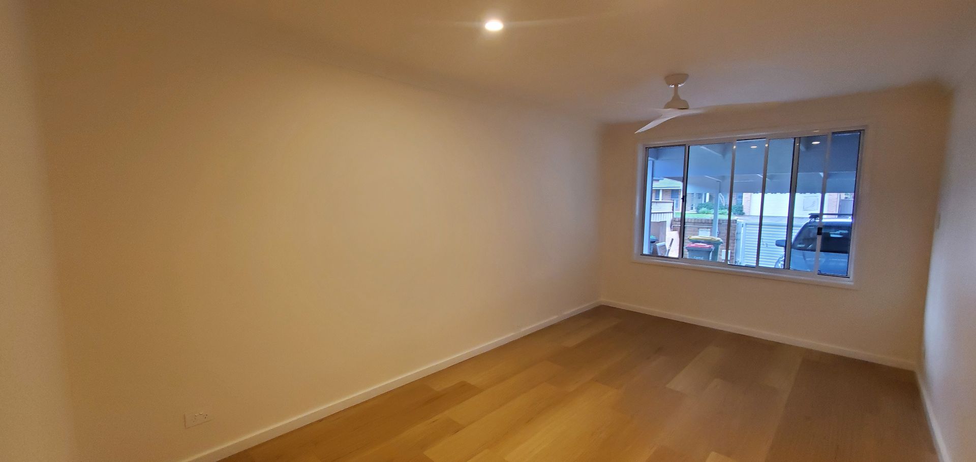An Empty Room With Hardwood Floors and a Ceiling Fan — JWP Painting & Property Services in Ettalong Beach, NSW