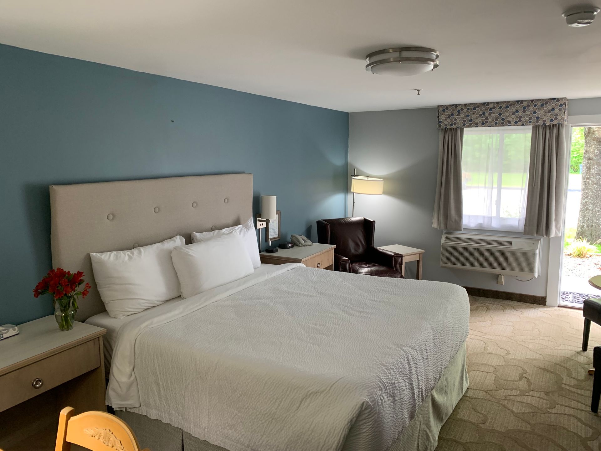 A hotel room with a king size bed , chairs and a table.