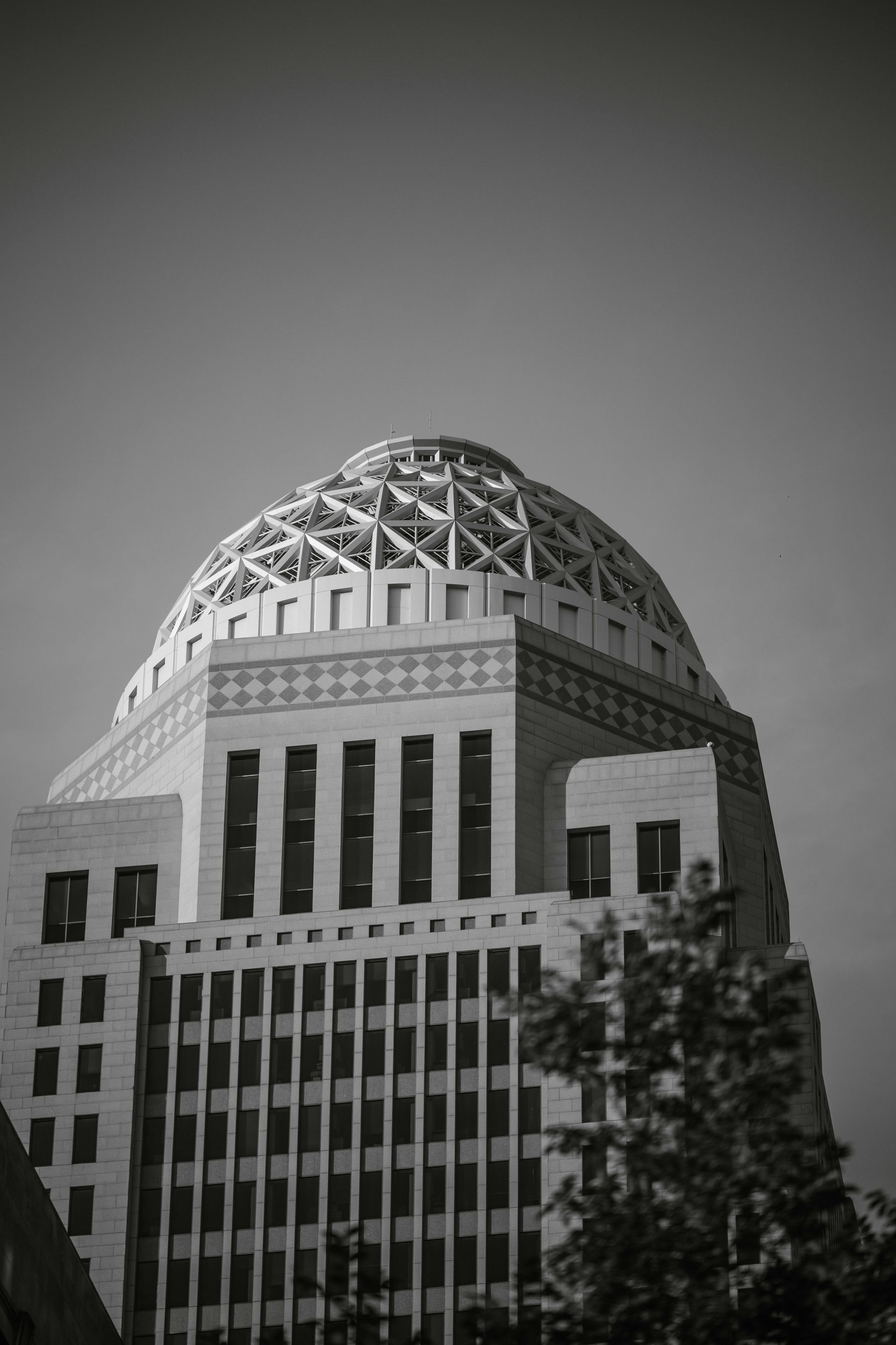 Black and white photo of a tall building with a rounded, latticed roof.