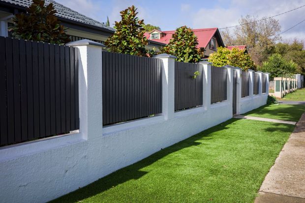 Black fence with white pillars and base, green lawn, residential setting. Black fence with white pillars and base, green lawn, residential setting.