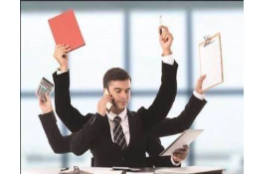 Stressed office worker juggling phone, papers, and folders at a desk, with multiple arms