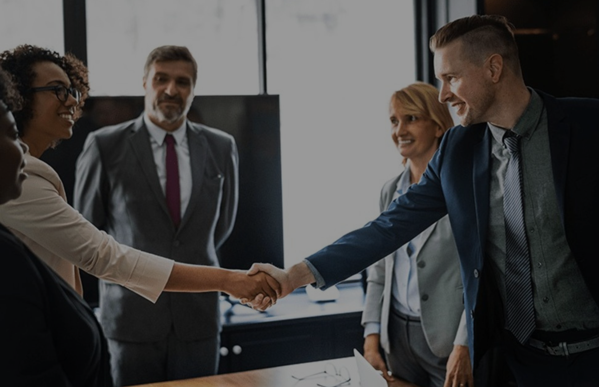 Colleagues in business attire shaking hands during a meeting in a conference room