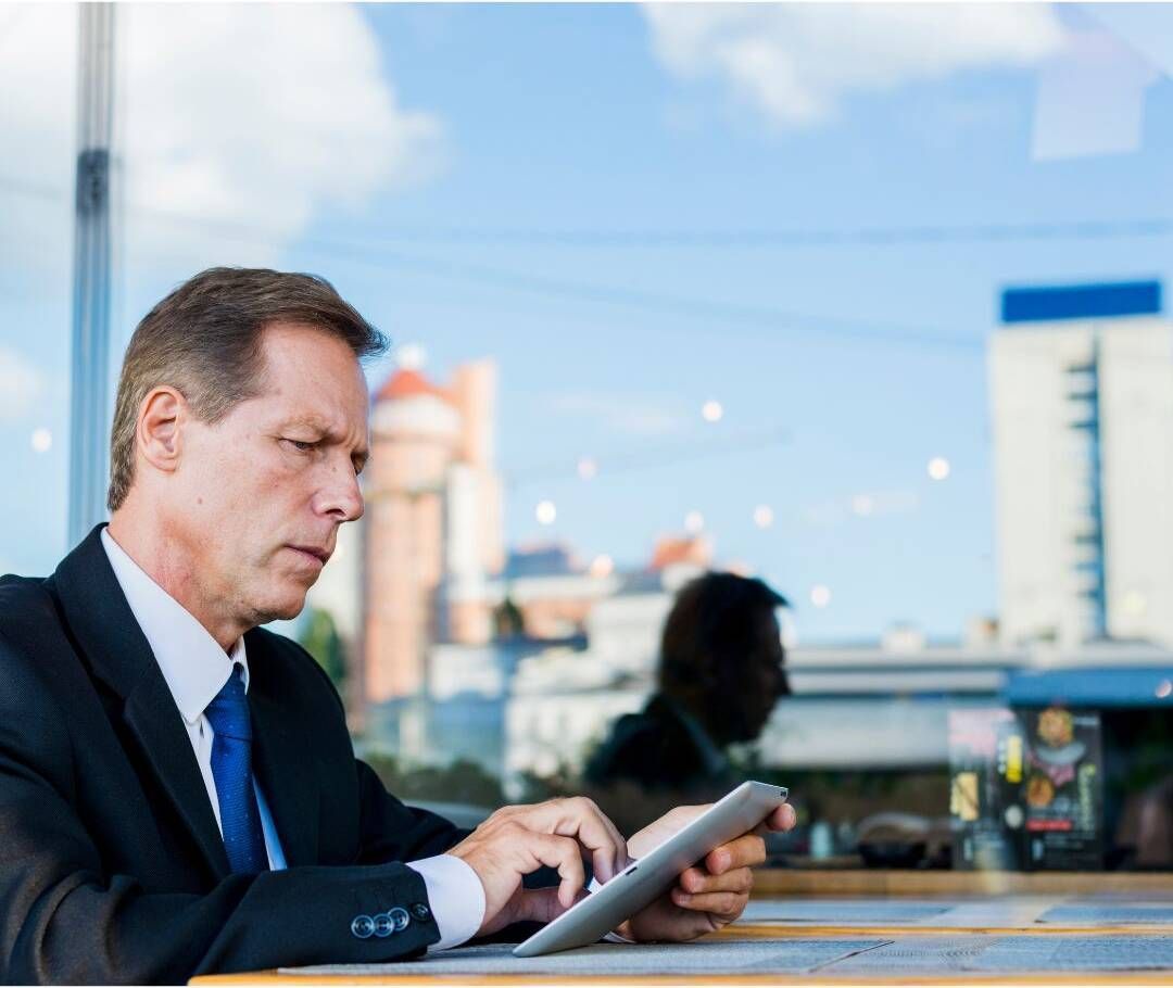 Businessman using a tablet at a cafe with a city skyline in the background