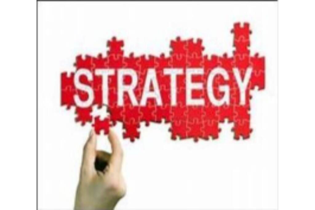 Hand placing red puzzle pieces to form the word “STRATEGY” on a white background