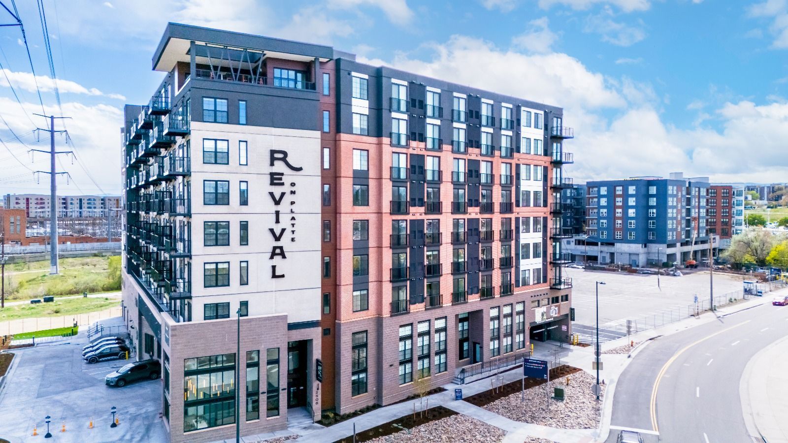 Exterior of the Revival Apartments building with dark brick and blue accents under a blue sky.