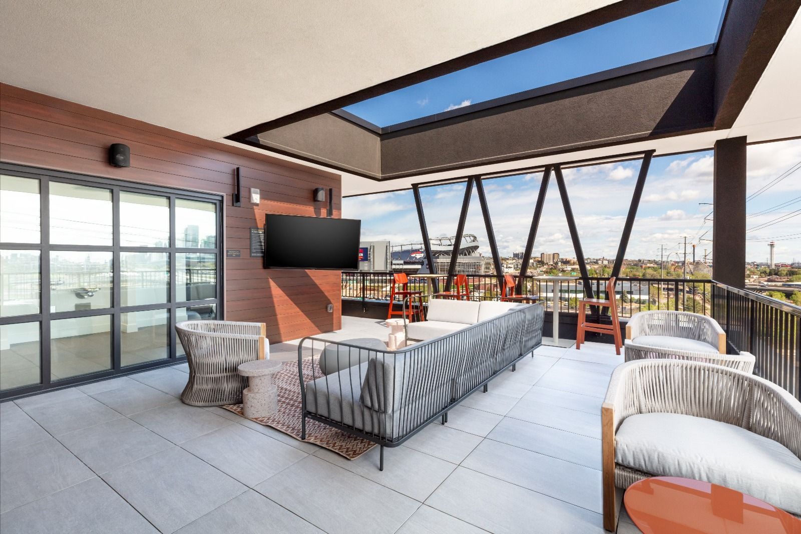 Rooftop patio with seating, television, and skylight overlooking city skyline.