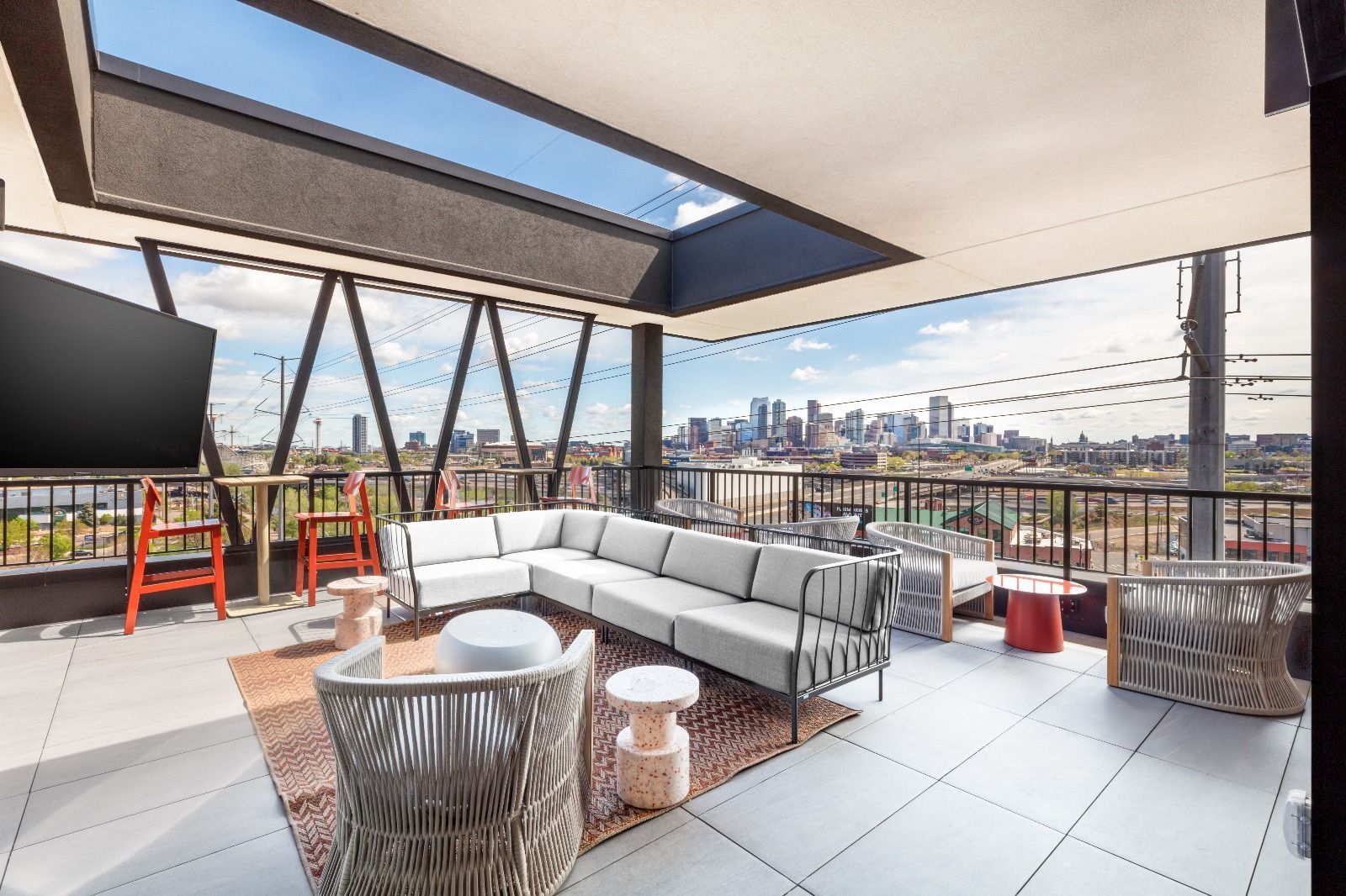 Rooftop patio with sectional seating, city skyline view, and skylight.
