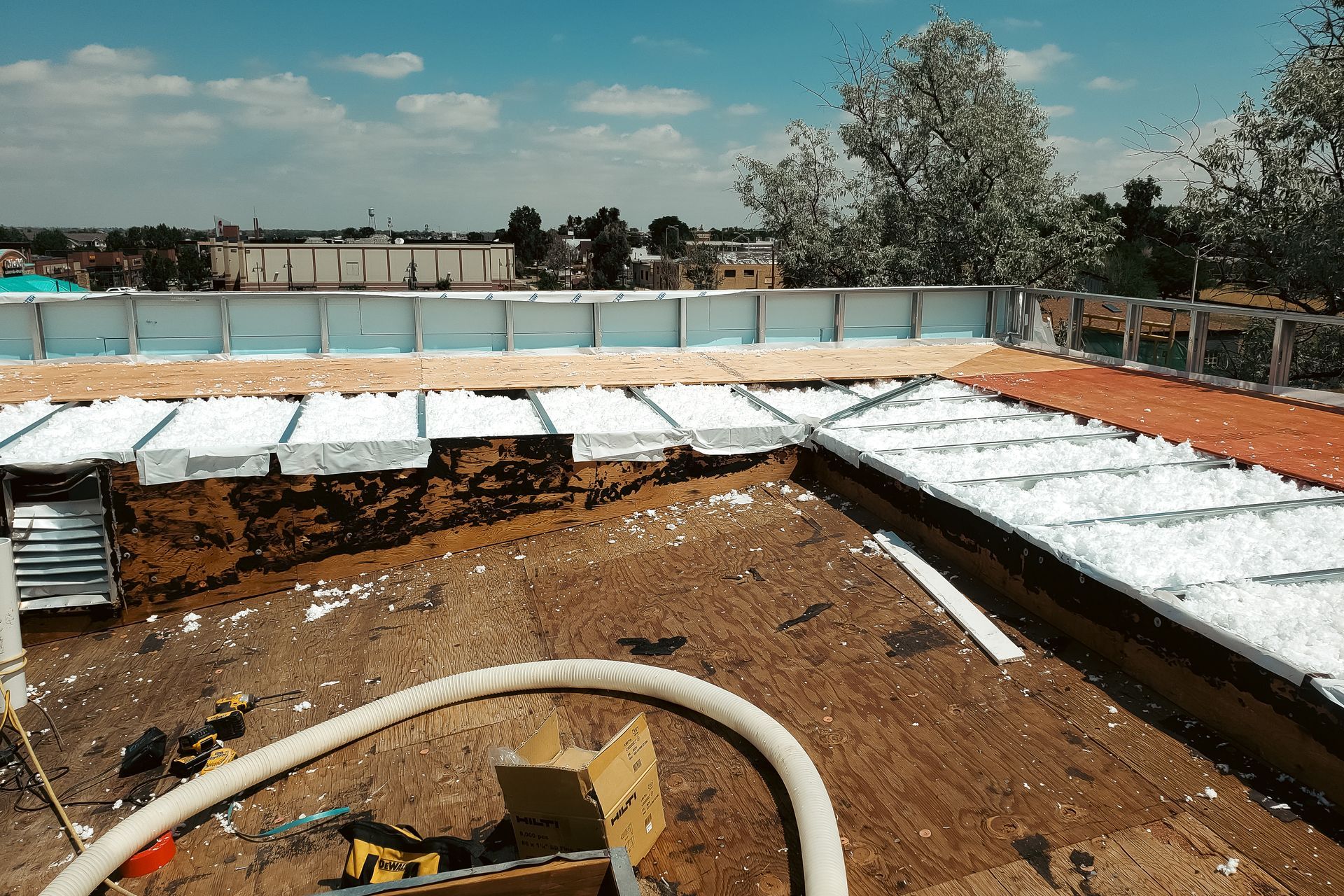 A hose is laying on the ground in front of a building under construction.