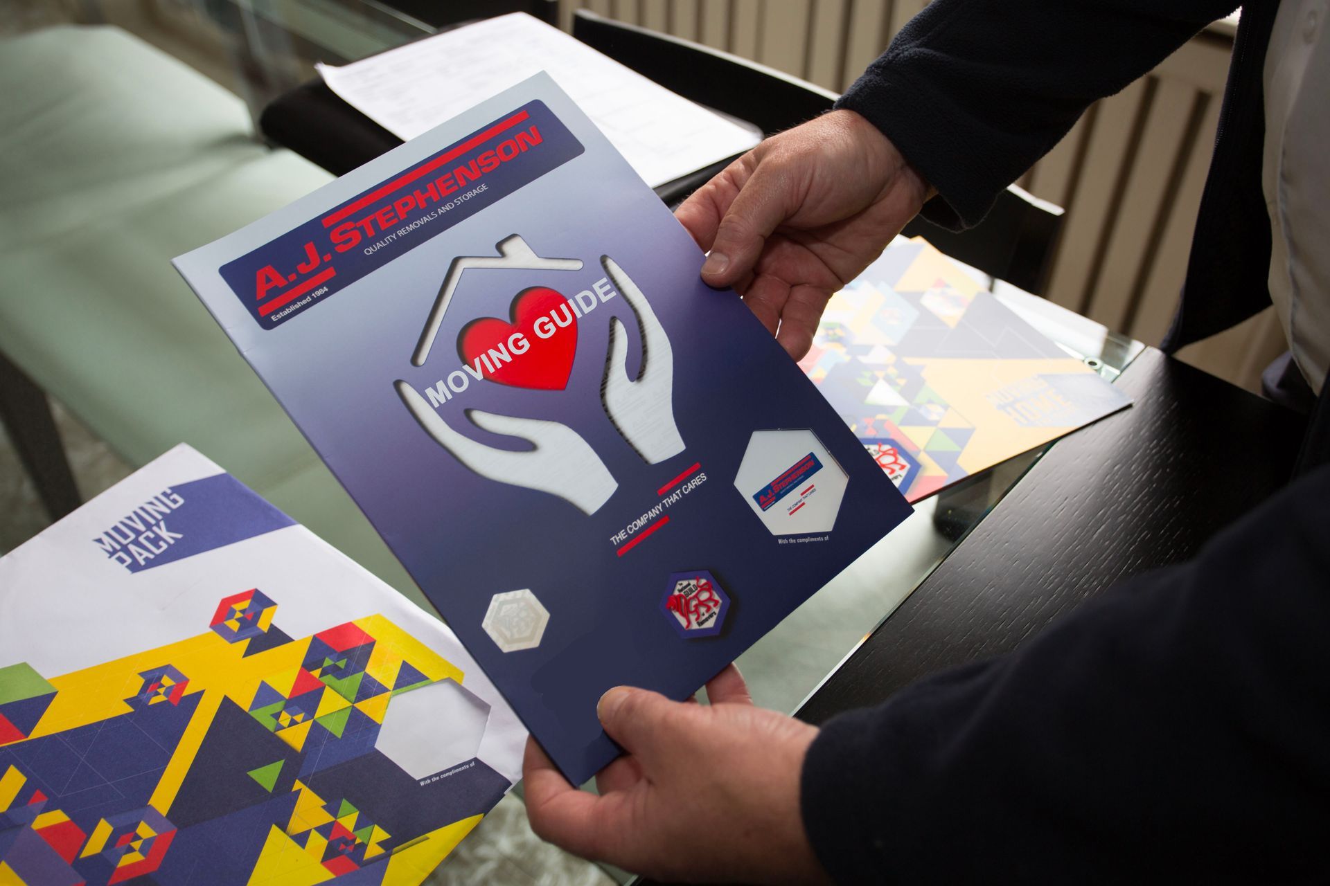 A person is holding a moving guide of AJ Stephenson Removals