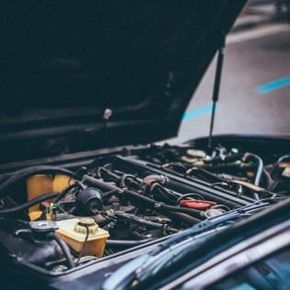 Open car hood showing the engine bay with hoses, wires, and fluid reservoirs.