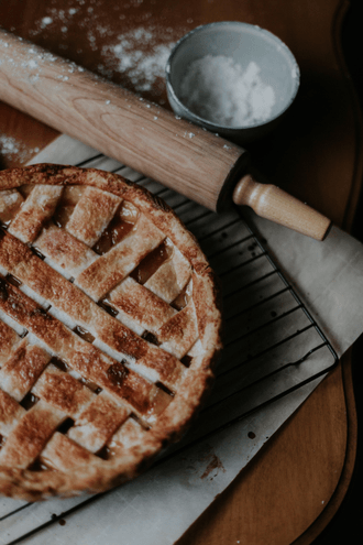 a pie is sitting on a cooling rack next to a rolling pin