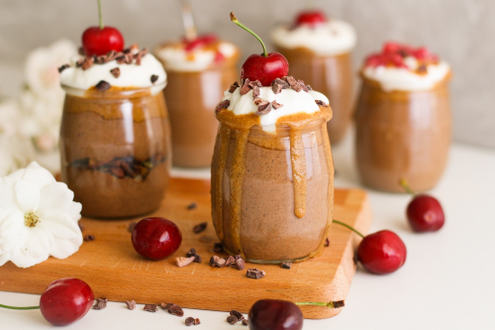 a jar of chocolate pudding with whipped cream and a cherry on top