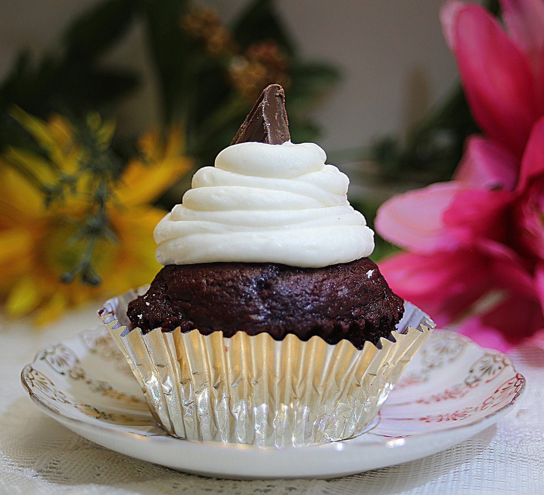 a chocolate cupcake with white frosting and a peanut butter cup on top