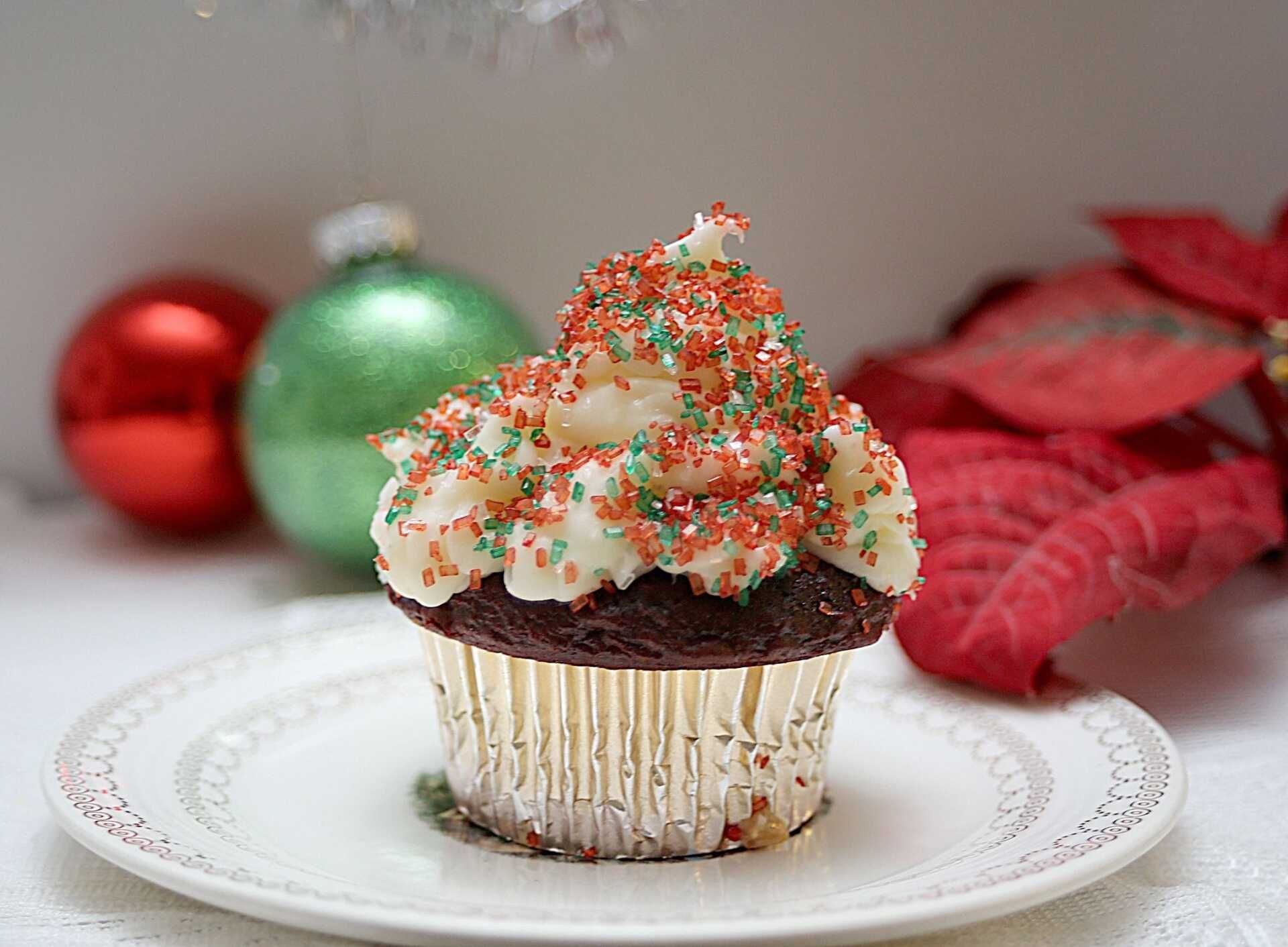 a cupcake with white frosting and red and green sprinkles