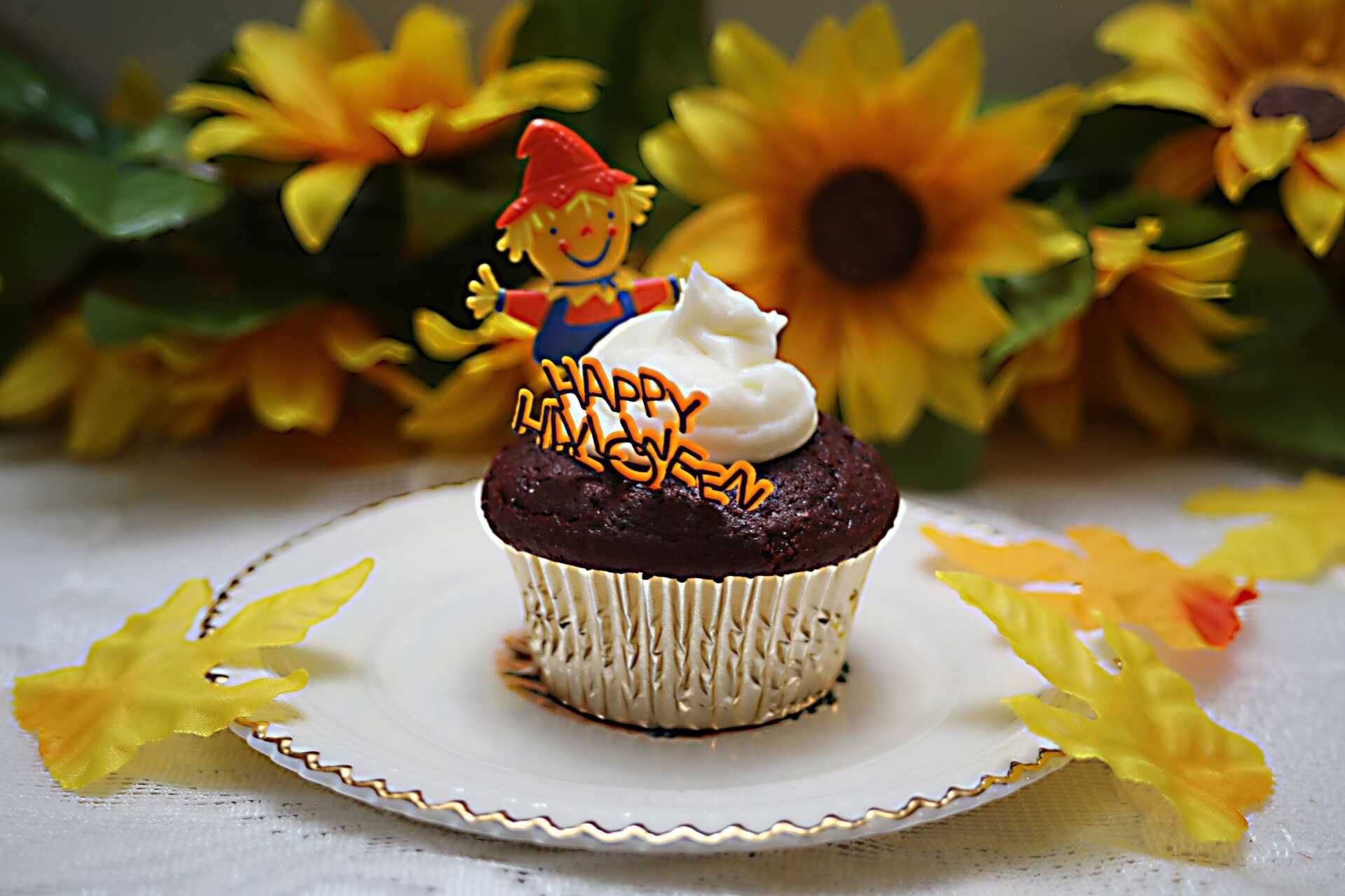 a cupcake with a scarecrow on top that says happy halloween