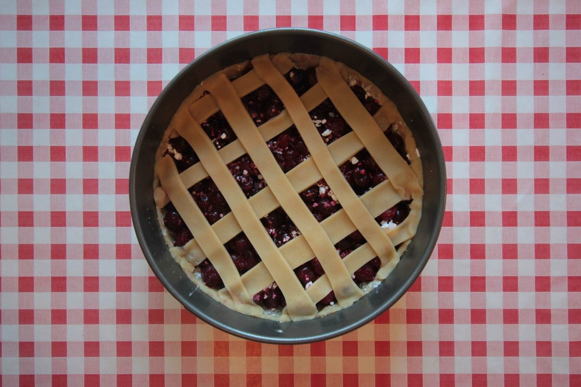 a pie with a lattice crust is sitting on a checkered table cloth