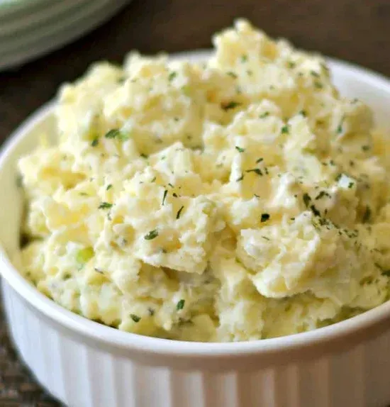 a close up of a bowl of potato salad on a table .