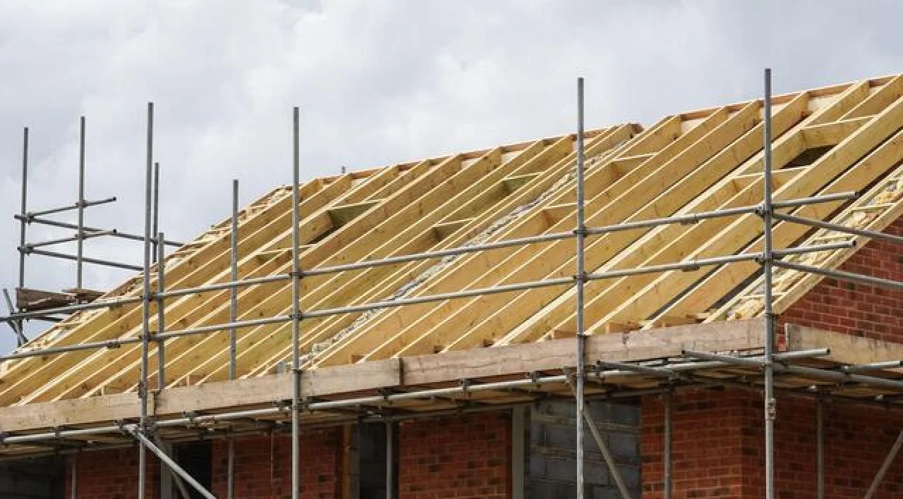 House roof under construction with scaffolding and yellow insulation panels