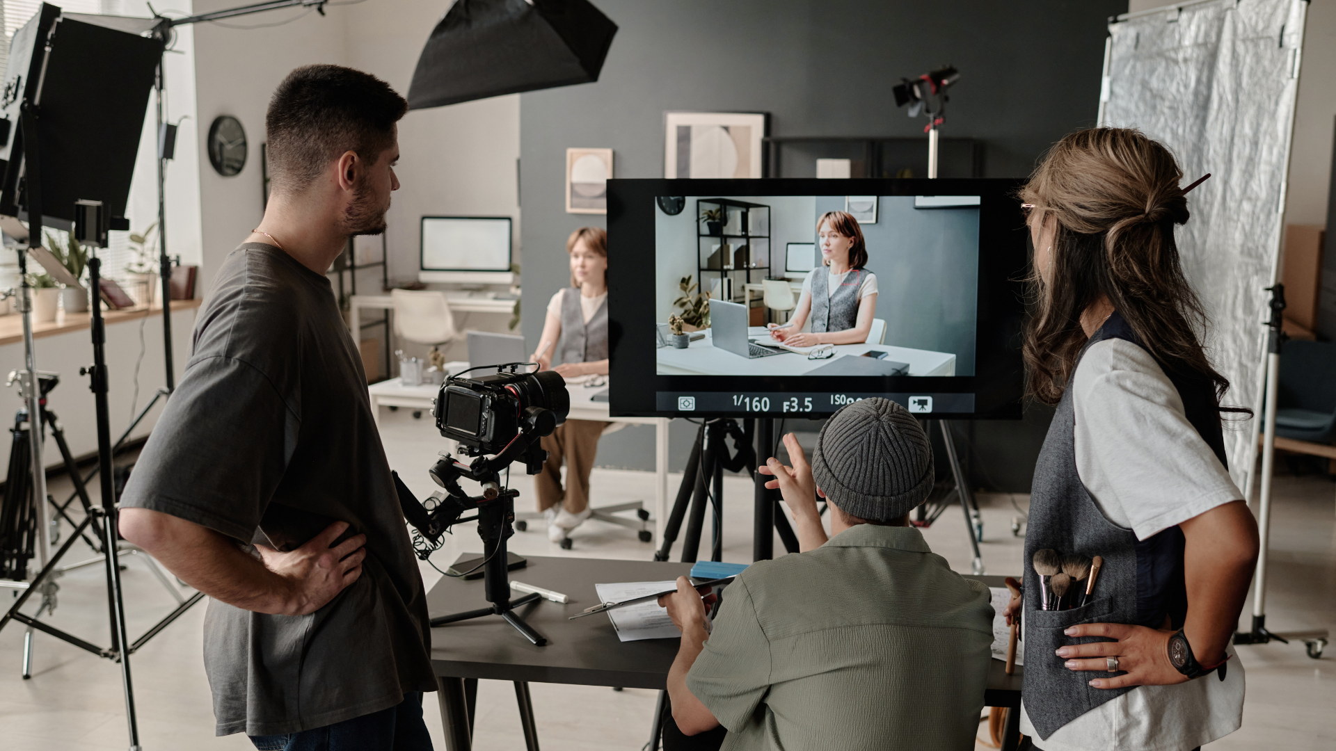 Film crew reviewing a shot on set with camera, lights, and monitor displaying a woman in a scene