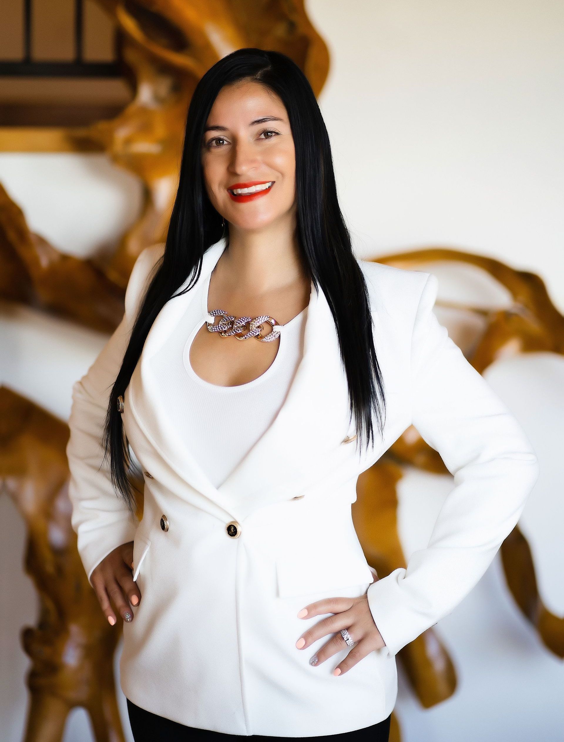 A woman in a white jacket is standing with her hands on her hips.