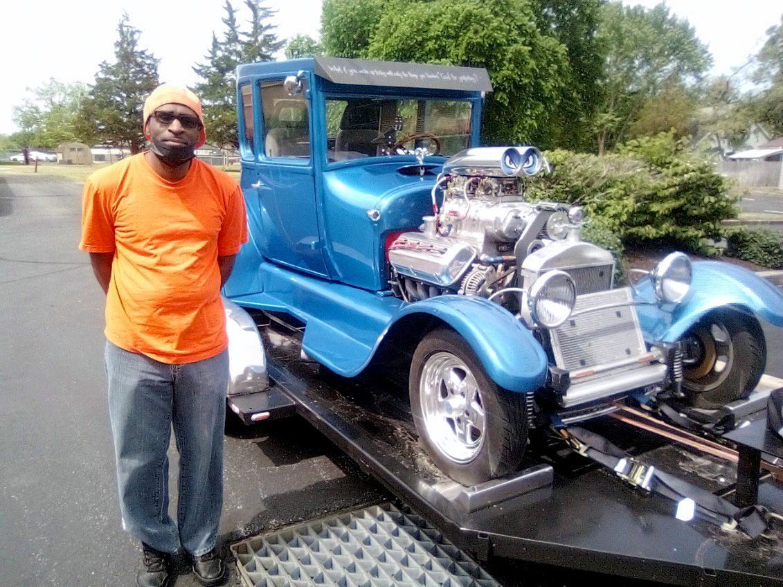 S. Owens standing next to bright blue old vehicle in great condition (2026)