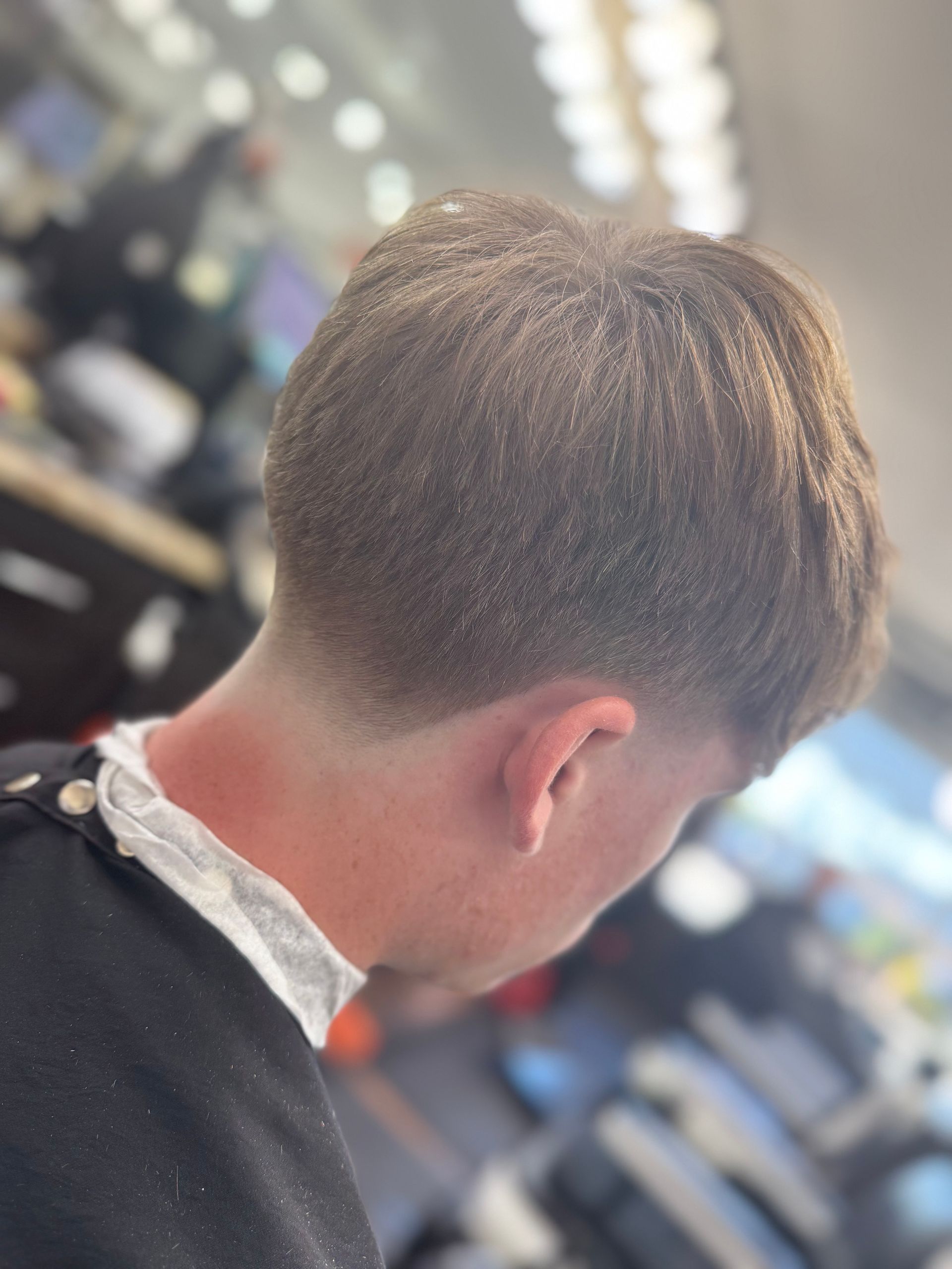 Person with a faded haircut, neck and ear visible, in a barber shop setting.