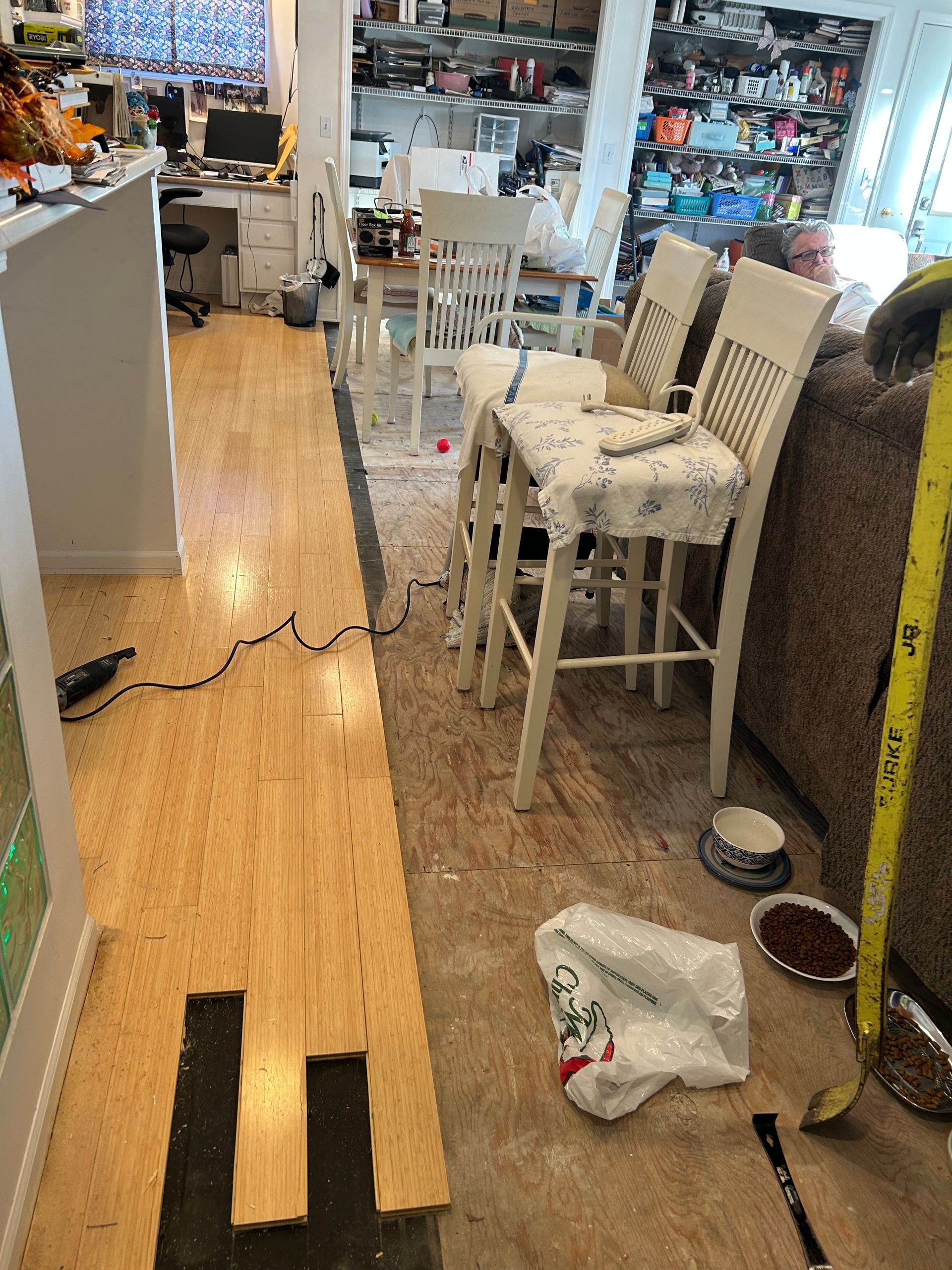Flooring installation in a kitchen.  Bamboo flooring partially installed with chairs and tools nearby.