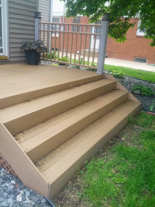 Composite deck with three steps, railing, and potted plant.