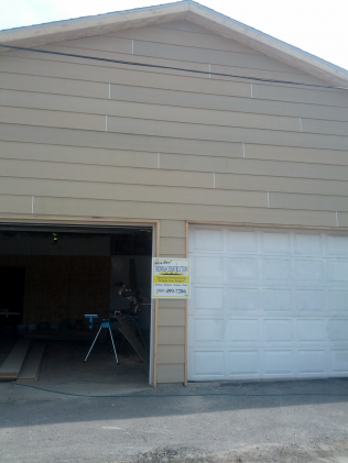 Tan garage with two bays; one open, the other with a closed white door.