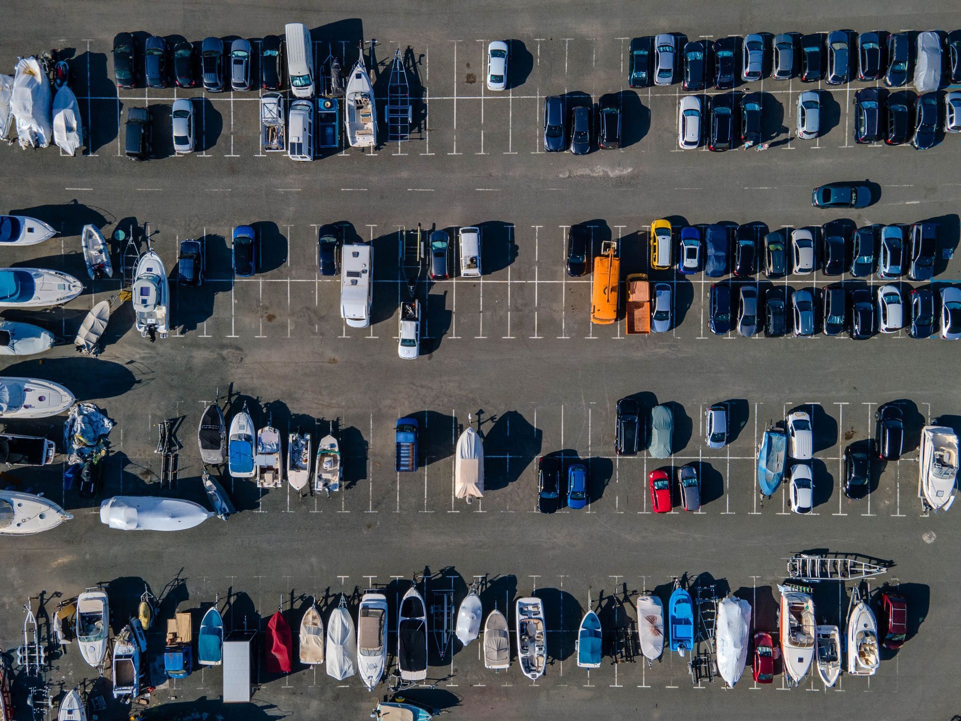 Aerial view of a parking lot filled with parked cars and boats.