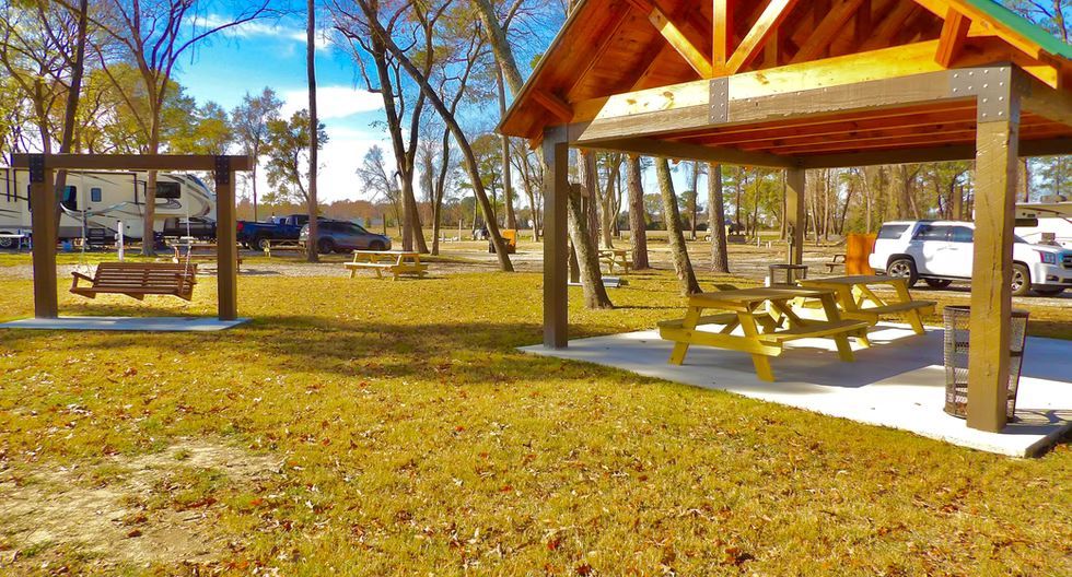 Park pavilion with picnic tables in a sunny autumn park, with trees and grass around it