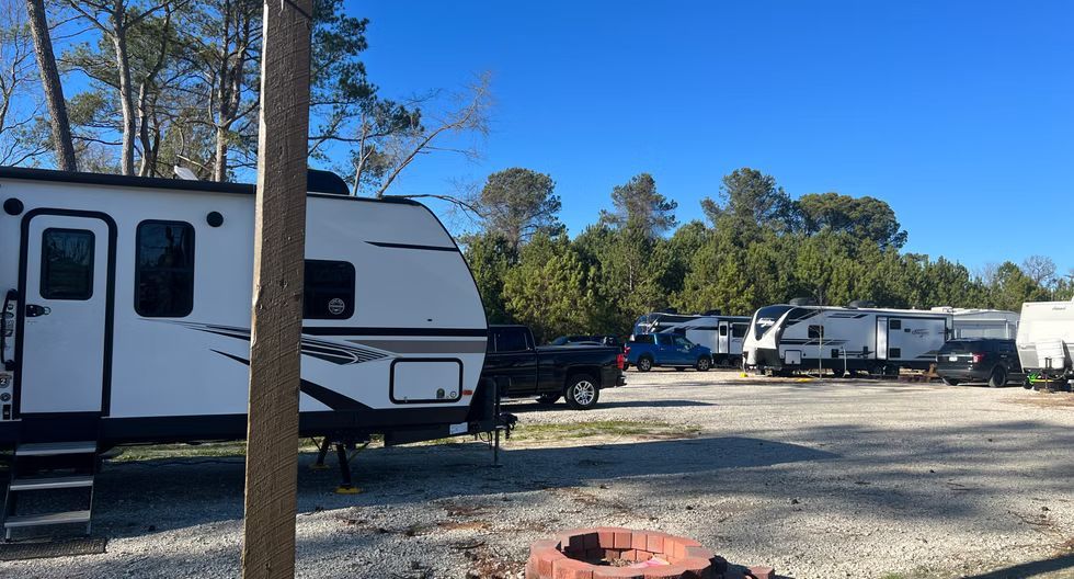 RV campground with several white trailers parked on gravel under a clear blue sky
