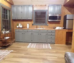 Kitchen with gray cabinets, wood-paneled walls, stainless fridge, and a window over the counter.