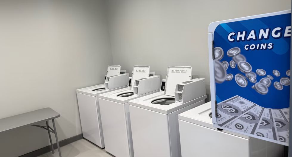 Row of coin change machines beside a blue coin changer in a plain room