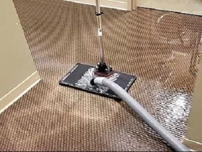 A vacuum cleaner is being used to clean a carpet in a room.