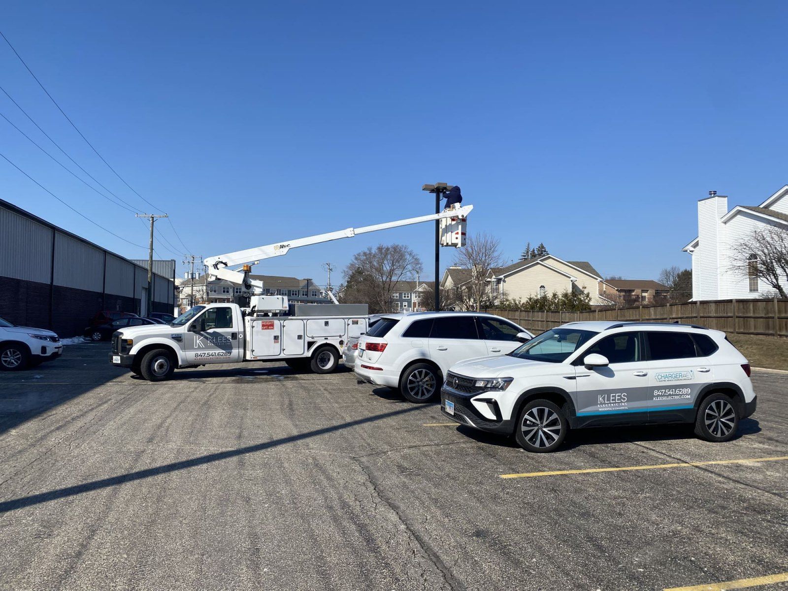 A couple of Klees electric inc cars are parked in a parking lot next to a Klees electric inc truck.