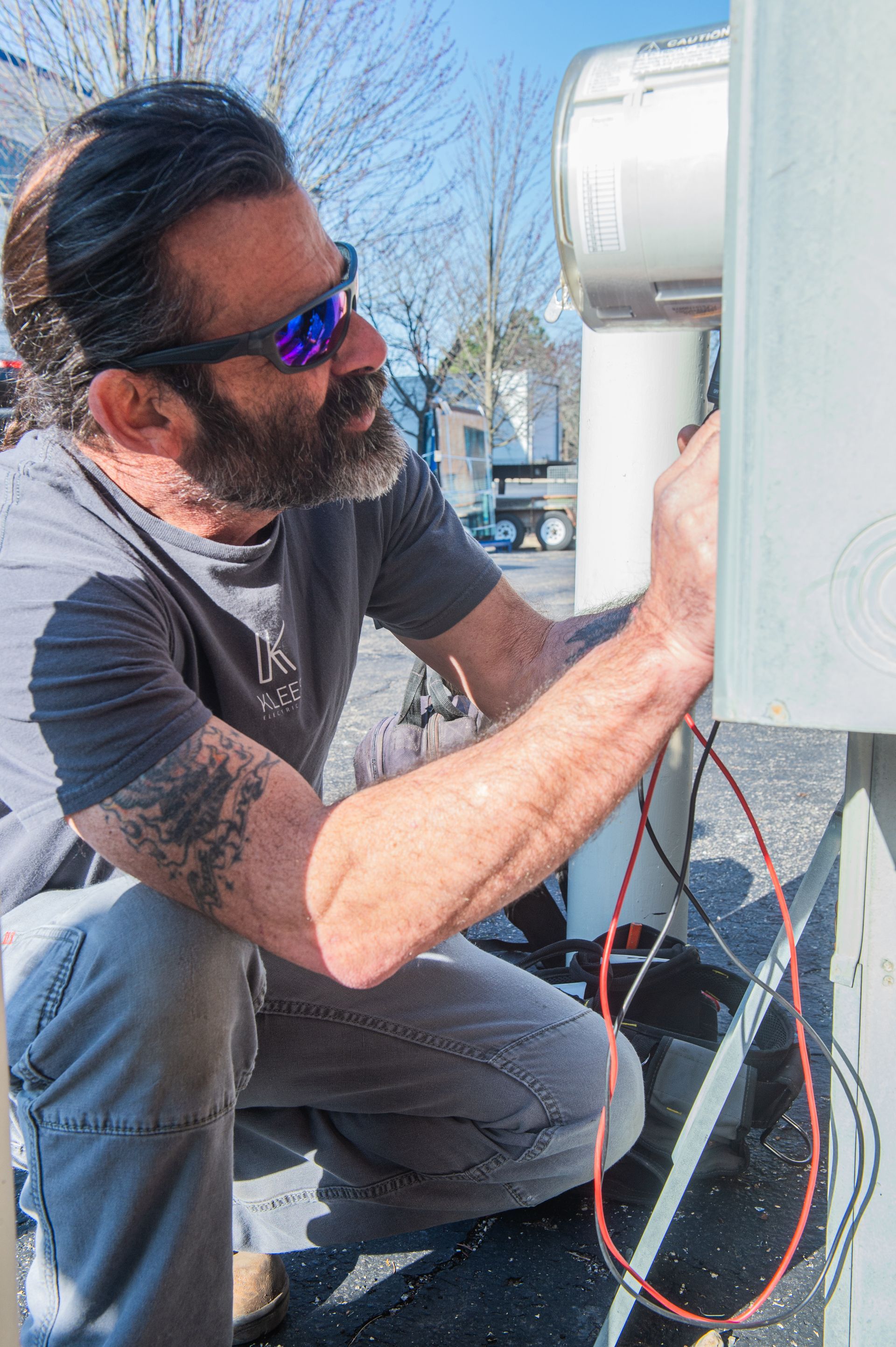 A man is working on an electrical box in a garage.