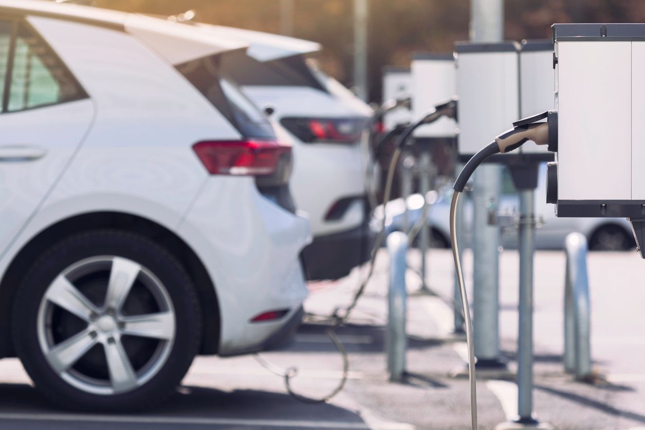 A white electric car is being charged at a charging station.
