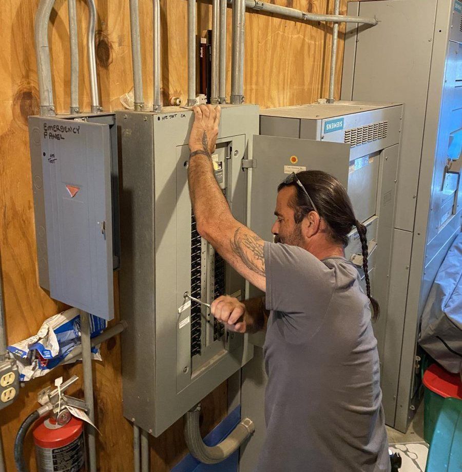 A man is working on an electrical box with a screwdriver