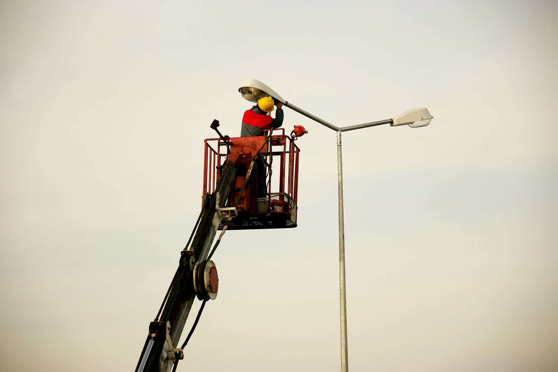 Electrician in bucket truck repairing and upgrading commercial light pole lighting.