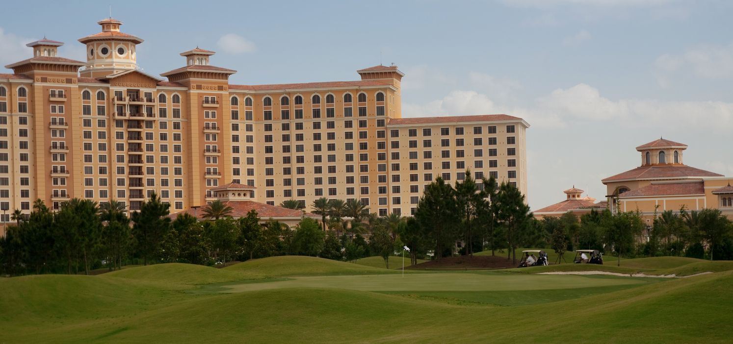 Large resort building overlooking a golf course, sunny day.