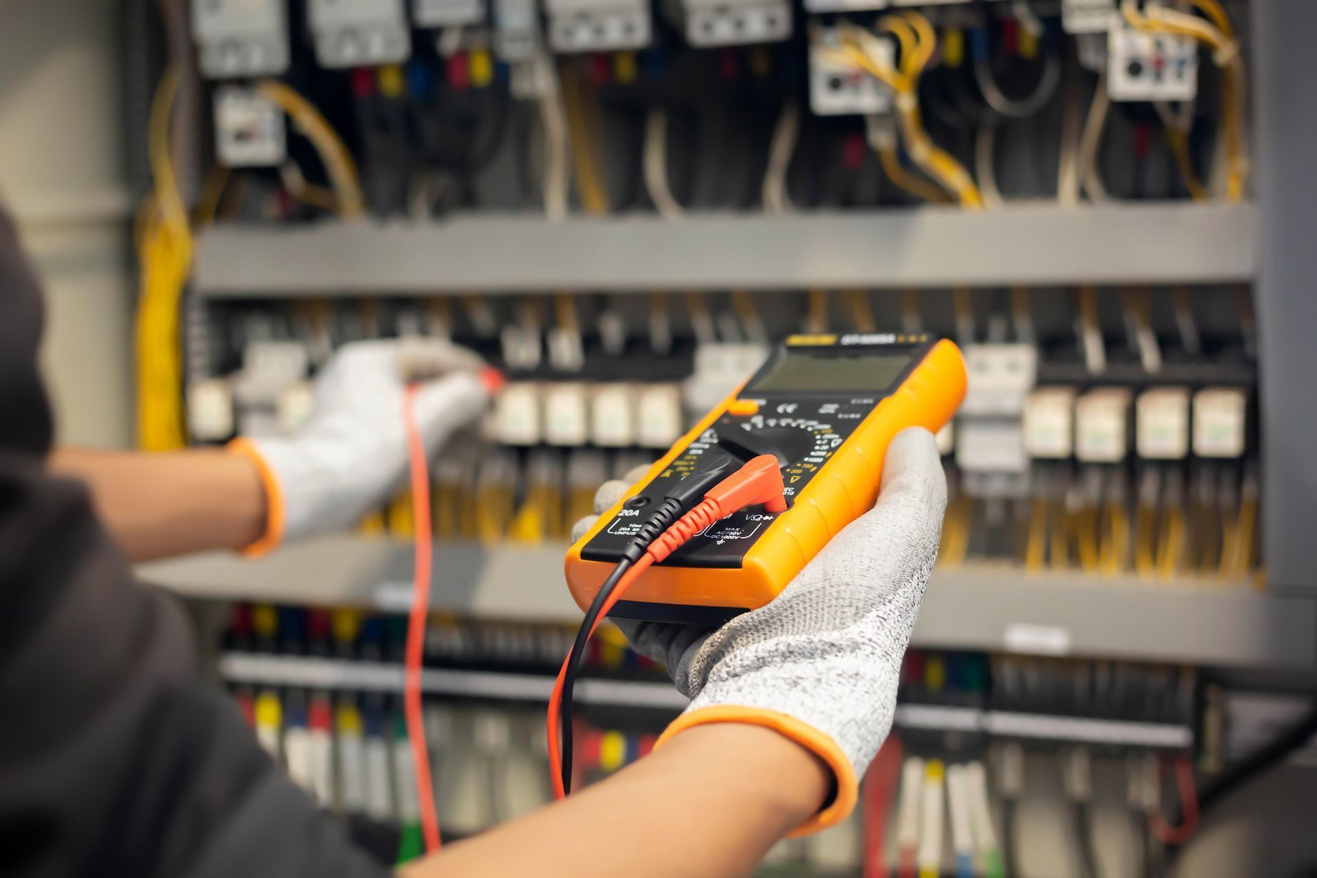 A close up of a person holding a multimeter in their hand.