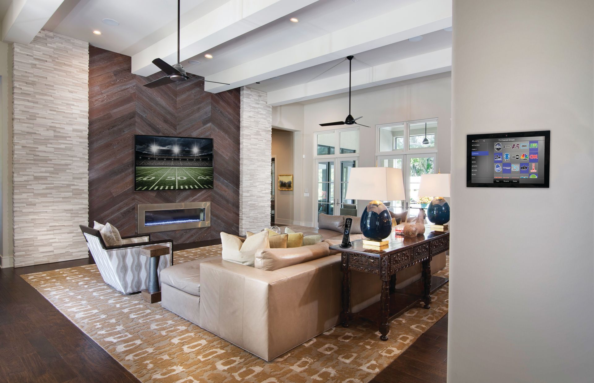 Modern living room with sectional sofa, TV, bar seating, and exposed brick fireplace.