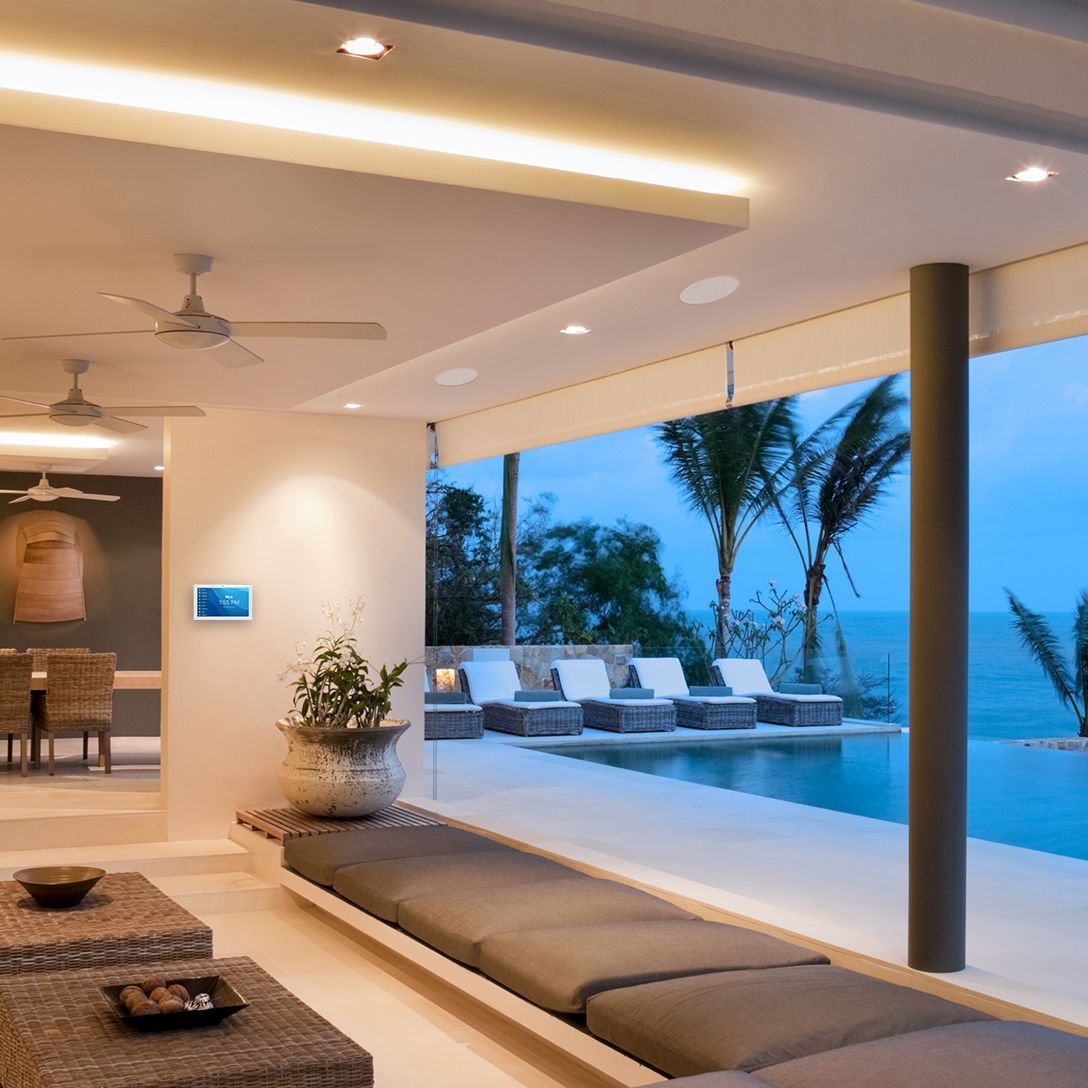 Modern beachfront lounge with cushioned seating, infinity pool, palm trees, and ocean view at dusk