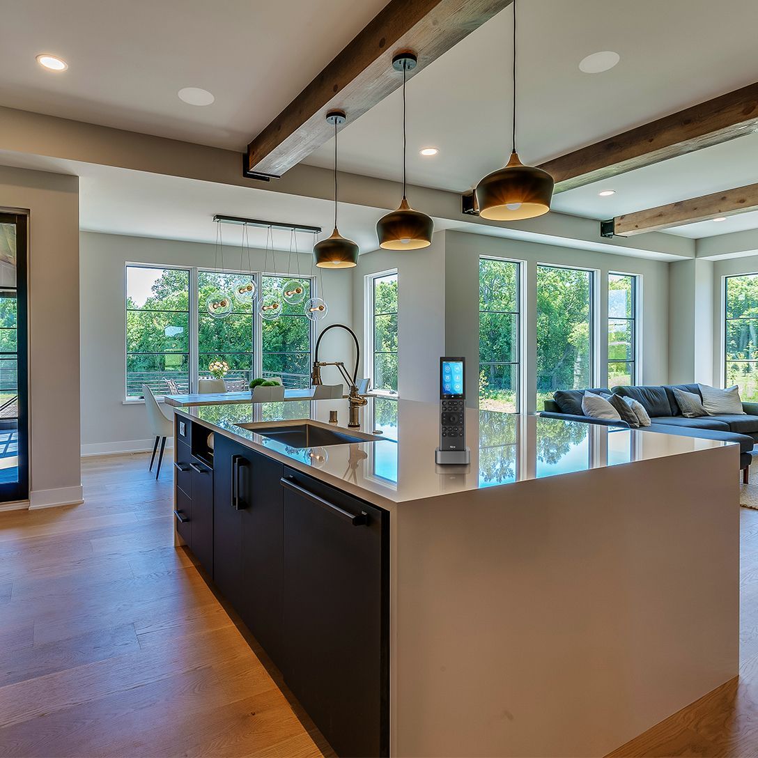 Modern kitchen with large island, pendant lights, and bright windows overlooking greenery