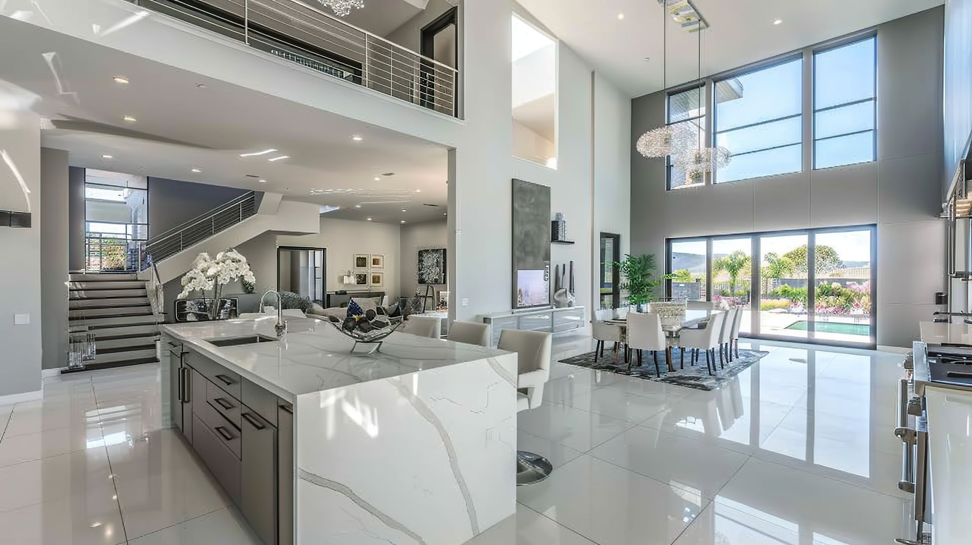 Modern open-concept luxury kitchen and living area with white floors, high ceilings, and large windows