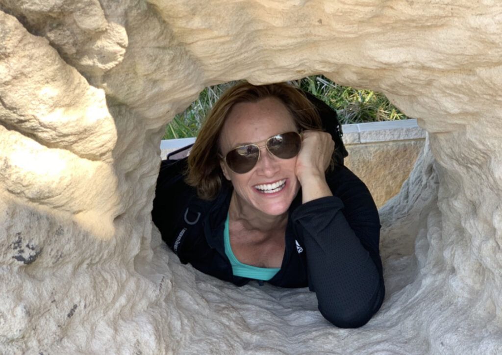 Woman Smiling Through a Rock Tunnel โ Michelle Crutcher Business Coaching & Consulting in The Entrance North, NSW